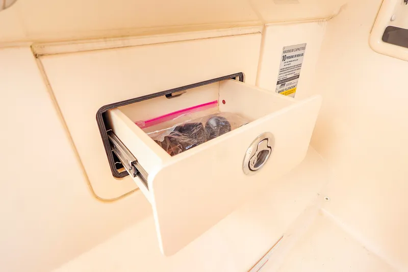 Slide: The Image of Storage compartment on 2020 Grady-White Freedom 235 boat, featuring a secure latch and interior items. - 14