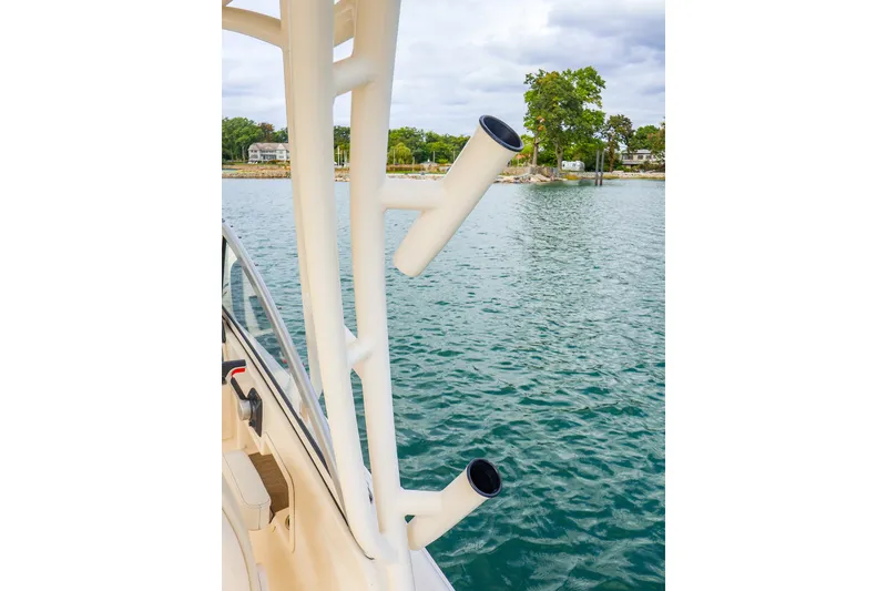 Slide: The Image of 2020 Grady-White Freedom 235 boat with rod holders, docked near a scenic shoreline. - 23