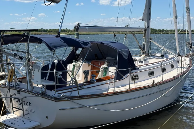 Slide: The Image of 1997 Island Packet 37 sailboat docked on a sunny day, featuring blue canvas covers. - 4