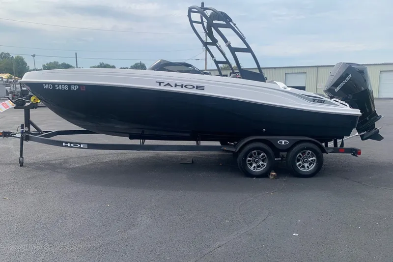 Slide: The Image of 2025 Tahoe T21 boat on trailer, black and white design, parked outdoors. - 1