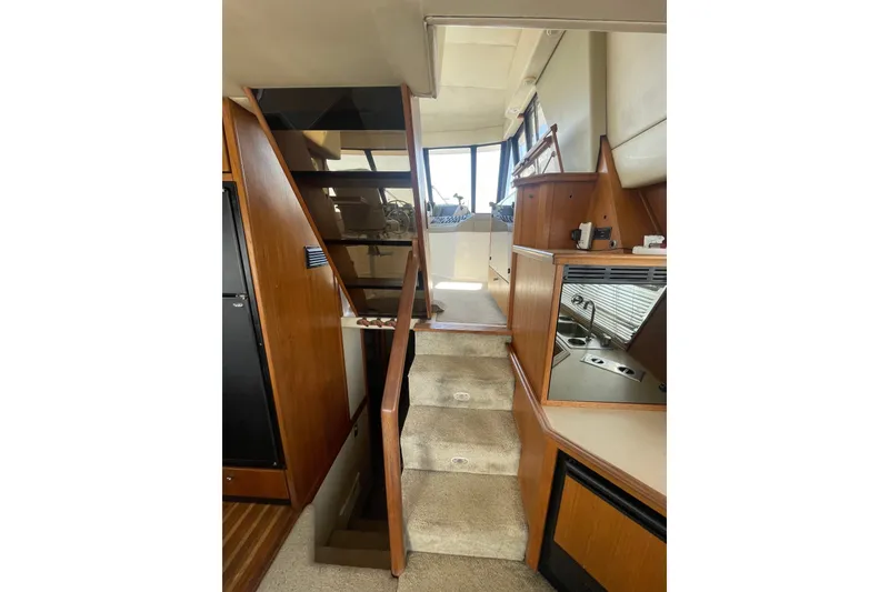 Slide: The Image of Interior view of 1995 Bayliner 4788 Pilot House Motoryacht, featuring stairs and wooden cabinetry. - 17
