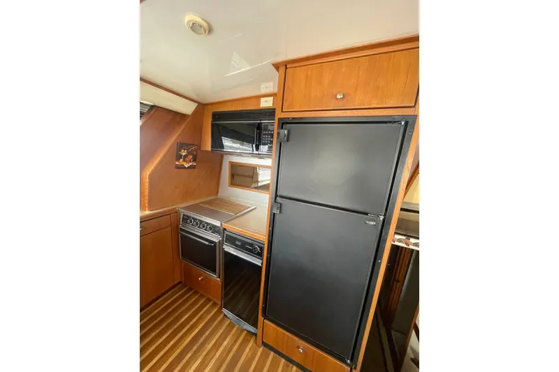 Slide: The Image of 1995 Bayliner 4788 Pilot House Motoryacht kitchen with stove, refrigerator, and microwave. - 13
