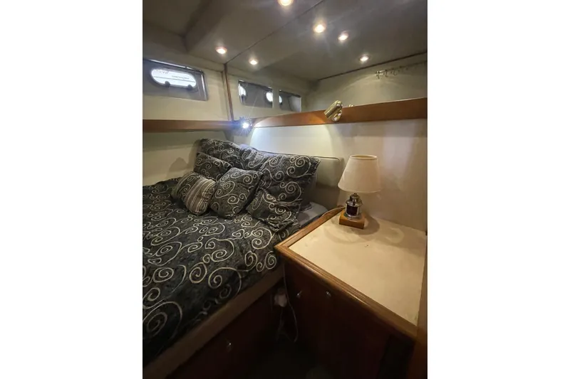 Slide: The Image of Cozy bedroom in 1995 Bayliner 4788 Pilot House Motoryacht with patterned bedding and bedside lamp. - 26