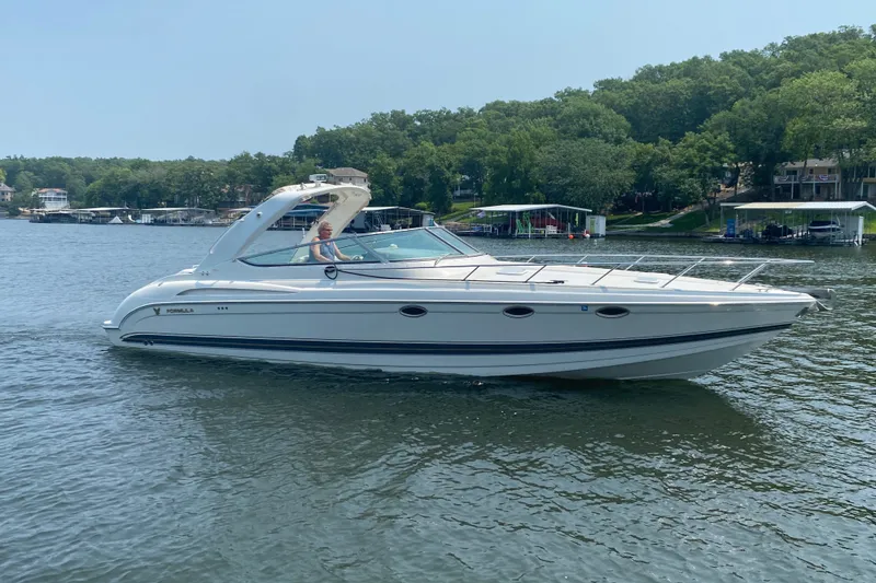 Slide: The Image of 2001 Formula 370 Super Sport boat cruising on a scenic lake with lush greenery. - 43