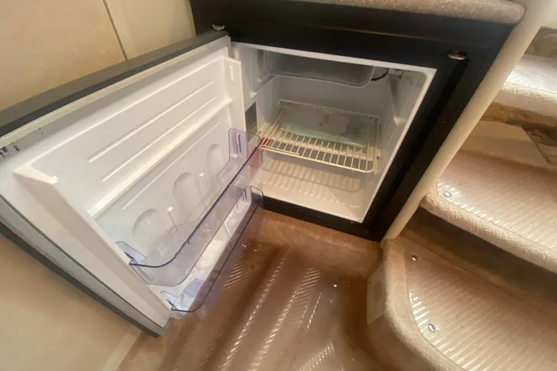 Slide: The Image of Open mini fridge inside a 2001 Formula 370 Super Sport boat, near carpeted stairs. - 37