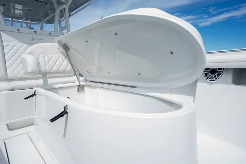 Slide: The Image of 2021 Yellowfin 36 Offshore boat with open storage compartment, white seating, and clear blue sky. - 25
