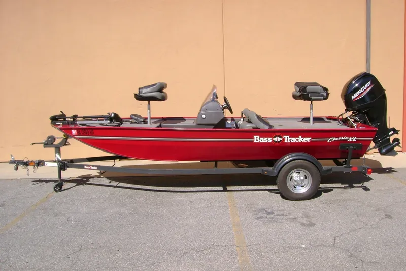 The Image of 2025 Bass Tracker Classic boat in red, parked on a trailer, side view. - 1