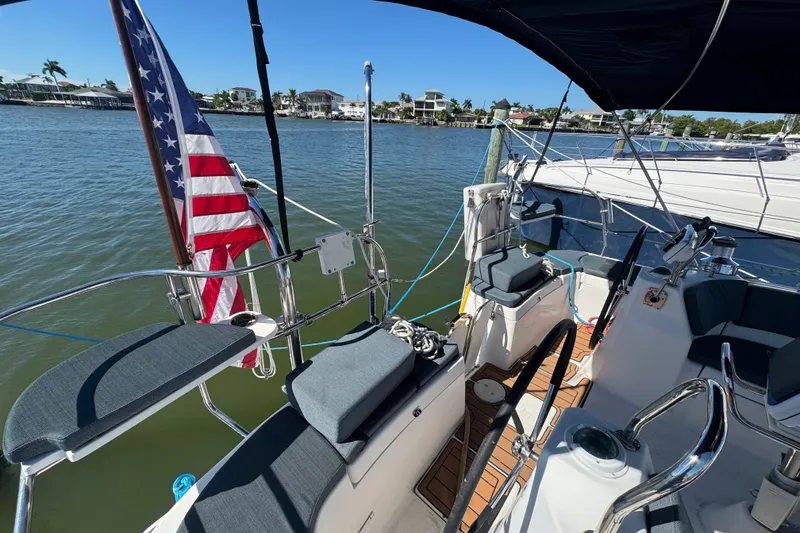 Slide: The Image of Hunter 49 sailboat cockpit with American flag, docked by waterfront homes, sunny day, 2009 model. - 106