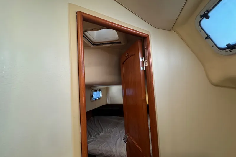 Slide: The Image of Interior cabin view of a 2009 Hunter 49 sailboat, featuring a wooden door and porthole. - 57