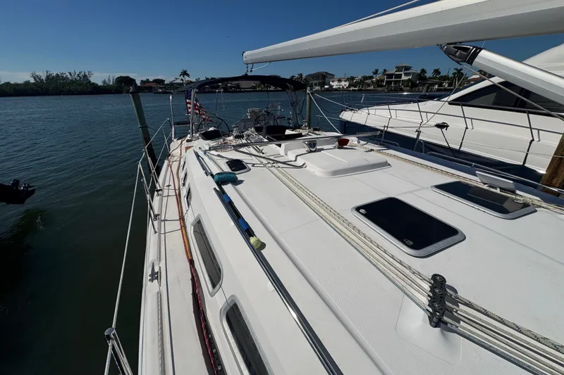 Slide: The Image of 2009 Hunter 49 sailboat docked, showcasing deck and rigging under clear blue sky. - 100