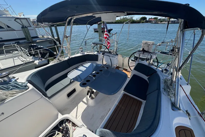 Slide: The Image of 2009 Hunter 49 sailboat cockpit with seating, table, and helm, docked in a marina. - 109