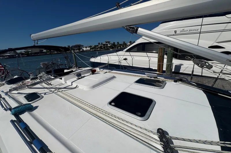 Slide: The Image of 2009 Hunter 49 sailboat deck with rigging, docked beside another vessel. - 101