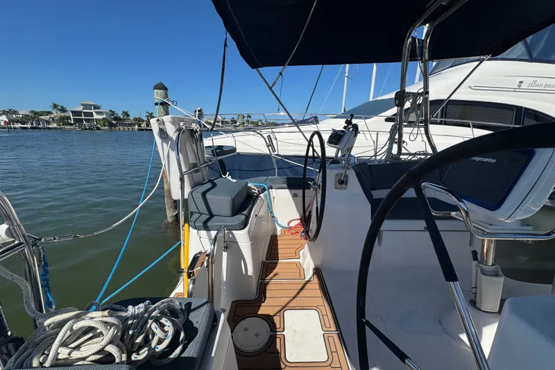Slide: The Image of 2009 Hunter 49 sailboat cockpit with steering wheel, docked by calm waters. - 107