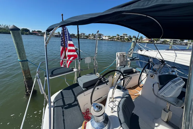 Slide: The Image of 2009 Hunter 49 sailboat cockpit with American flag, docked in sunny marina. - 105