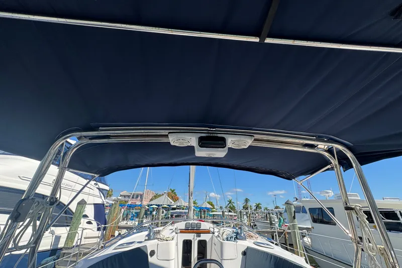 Slide: The Image of 2009 Hunter 49 sailboat cockpit with blue canopy, docked at marina under clear sky. - 84
