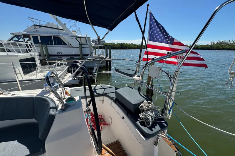 Slide: The Image of Cockpit of 2009 Hunter 49 sailboat with American flag, docked near other boats. - 79