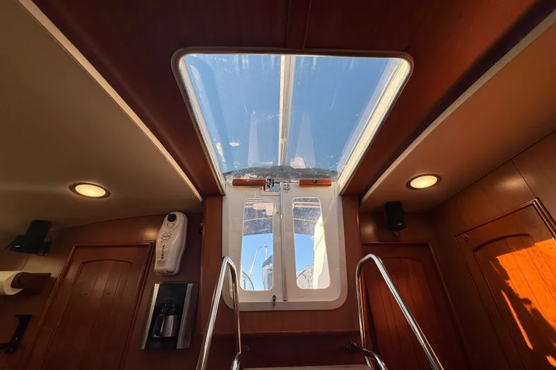Slide: The Image of Interior view of a 2009 Hunter 49 yacht, featuring a skylight and wooden paneling. - 69