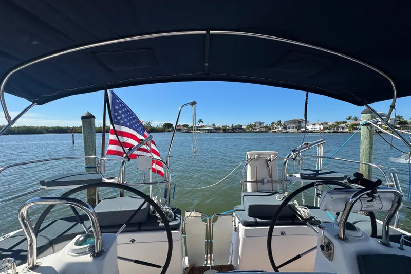 Slide: The Image of Cockpit view of 2009 Hunter 49 sailboat with American flag, docked by calm waters. - 76