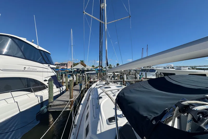 Slide: The Image of 2009 Hunter 49 sailboat docked at marina, clear blue sky, neighboring yachts visible. - 89