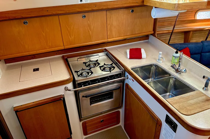 Slide: The Image of Compact kitchen in a 2000 Catalina 380 sailboat with stove, sink, and wooden cabinetry. - 8
