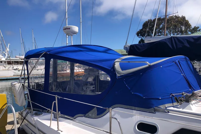 Slide: The Image of Catalina 380 sailboat from 2000 with blue canopy docked at marina. - 25