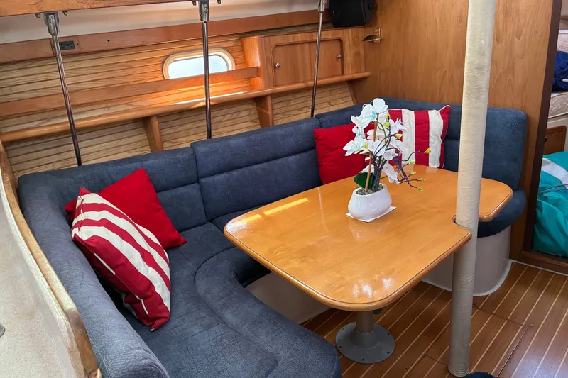 Slide: The Image of Cozy interior of a 2000 Catalina 380 sailboat with a wooden table and blue seating. - 4