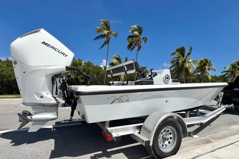 Slide: The Image of Custom Vtech 18 Flats 2025 boat with Mercury engine on trailer, palm trees in background. - 2