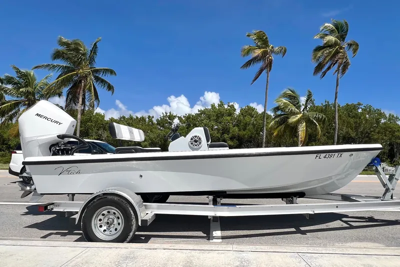 Slide: The Image of Custom Vtech 18 Flats boat on trailer, palm trees in background, 2025 model. - 1