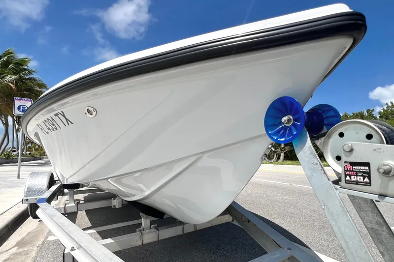 Slide: The Image of Custom Vtech 18 Flats boat on trailer, sunny day, palm trees in background. - 19