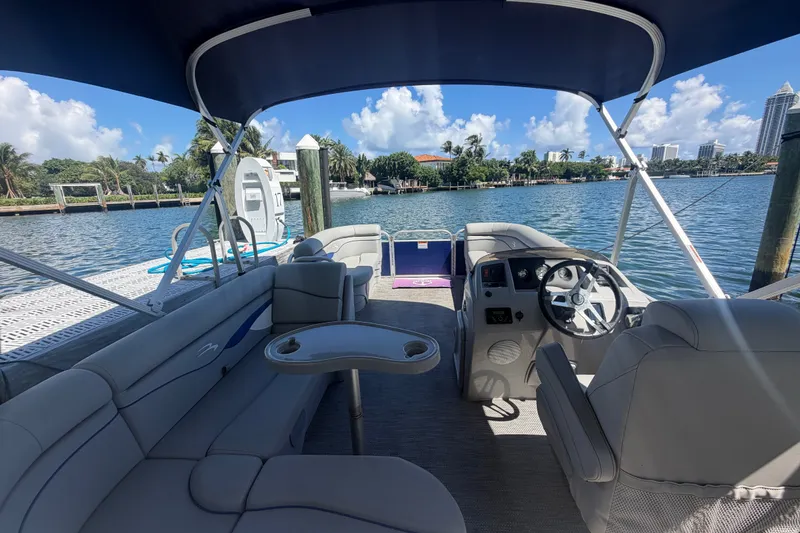 Slide: The Image of 2023 Bennington 20 SVL pontoon boat interior with seating and steering wheel, docked by the water. - 4