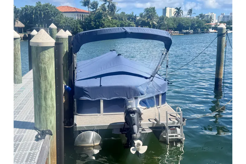 Slide: The Image of 2023 Bennington 20 SVL pontoon boat docked with blue cover and outboard motor. - 3