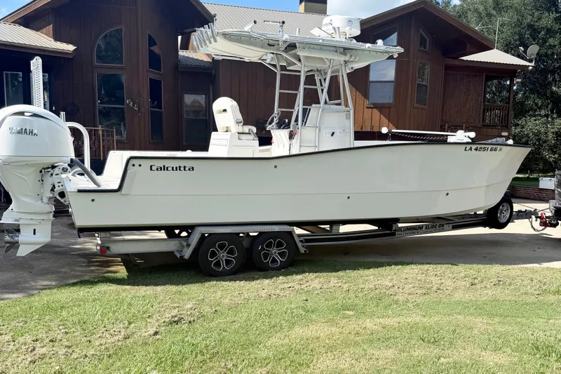 Slide: The Image of 2015 Calcutta 263 boat on trailer, parked near a wooden house, featuring Yamaha engine. - 4