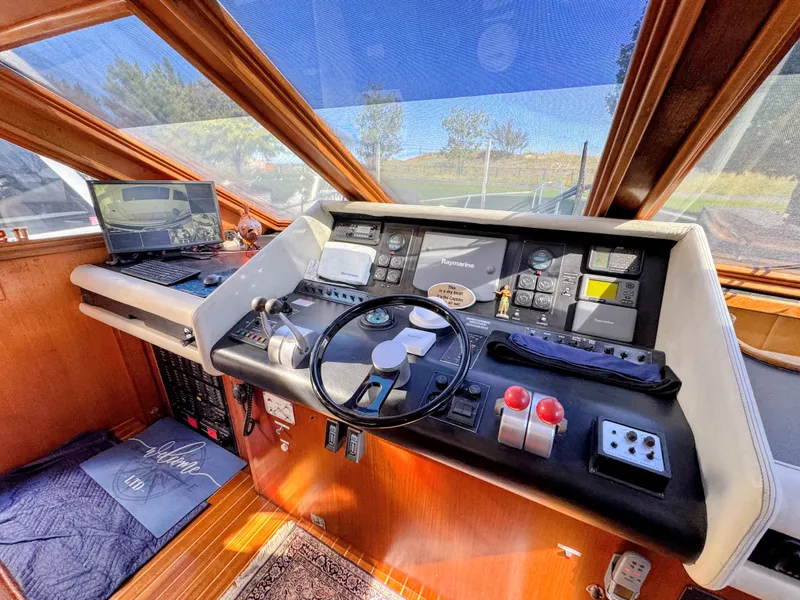 Slide: The Image of The cockpit of a 1990 Viking 55 Motor Yacht Wide Body with modern navigation equipment and a large steering wheel. - 22