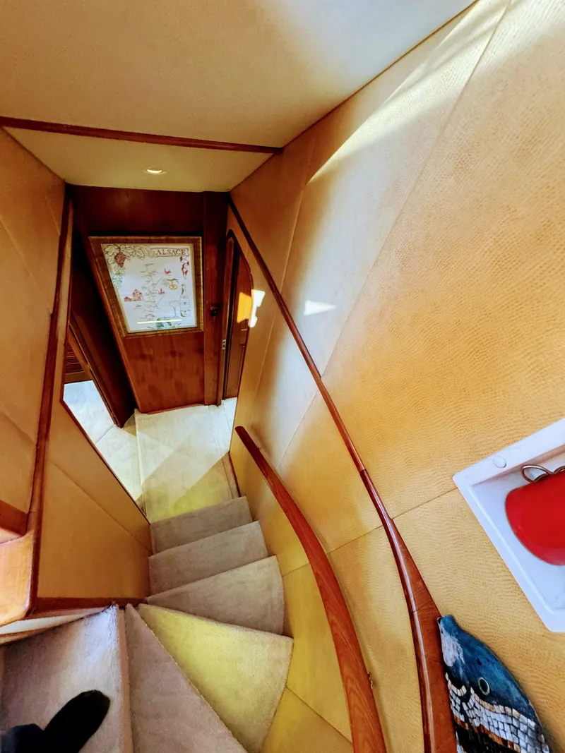 Slide: The Image of A stairway inside a yacht with carpeted steps and wooden walls. A door leads to another room. - 48