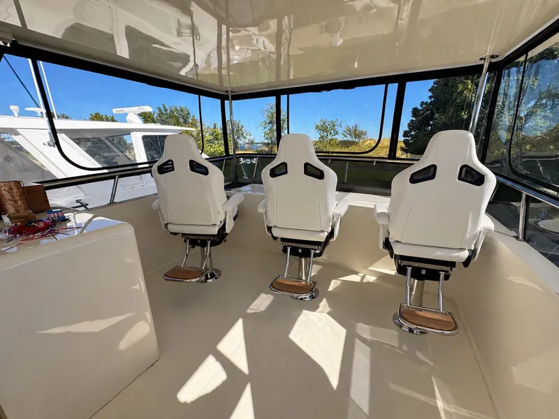Slide: The Image of The image shows a yacht's helm area with three white, modern seats and large windows. - 15
