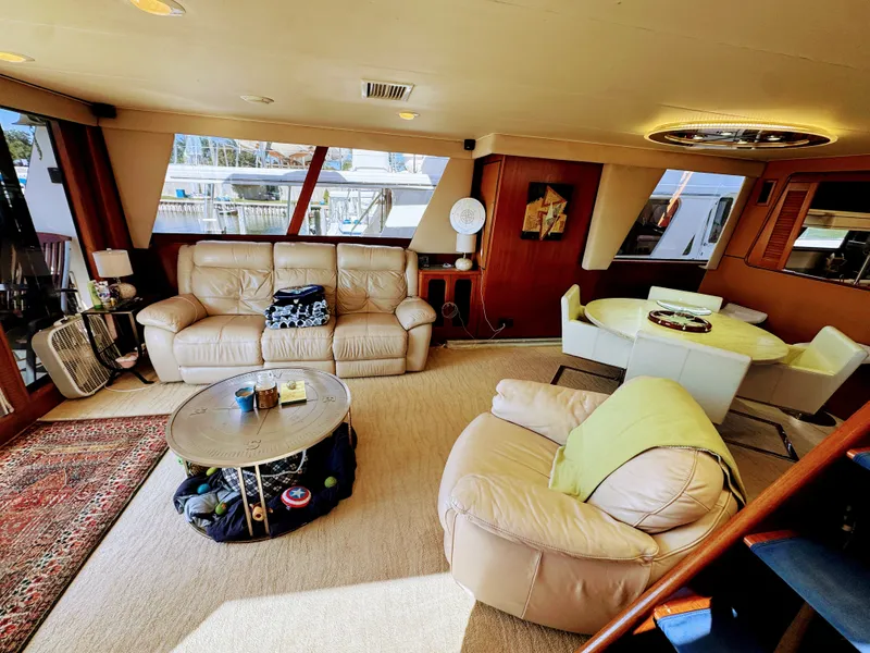 Slide: The Image of The interior of a 1990 Viking 55 Motor Yacht features a cozy living area with leather sofas and a round table. - 30