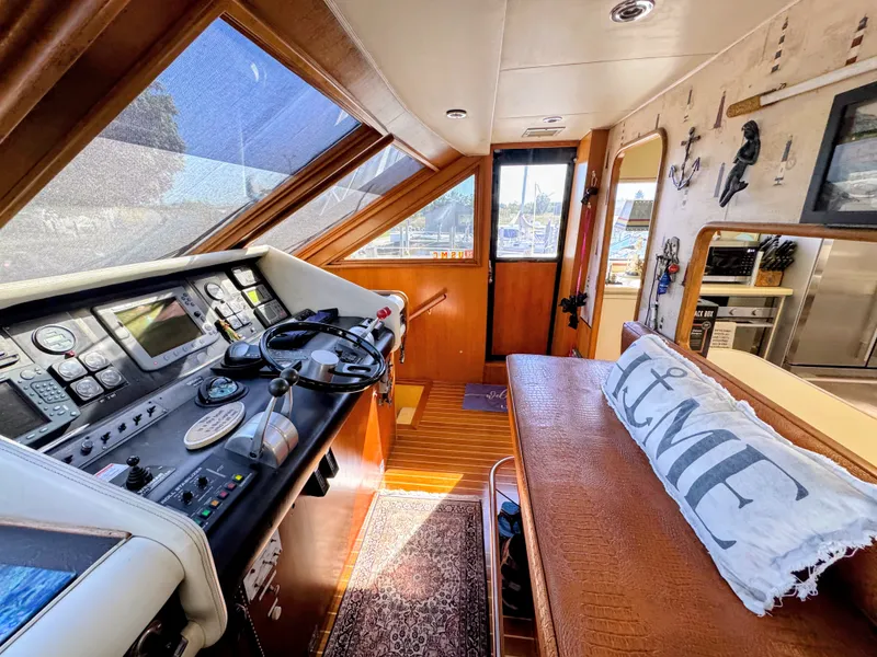 Slide: The Image of Interior view of a yacht with helm station, wooden flooring, and cozy seating area with a pillow. - 24