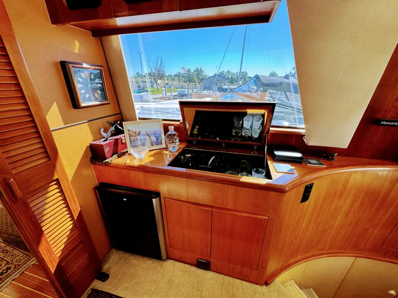 Slide: The Image of Yacht interior with wooden furnishings, a minibar, and a window overlooking the marina. - 33