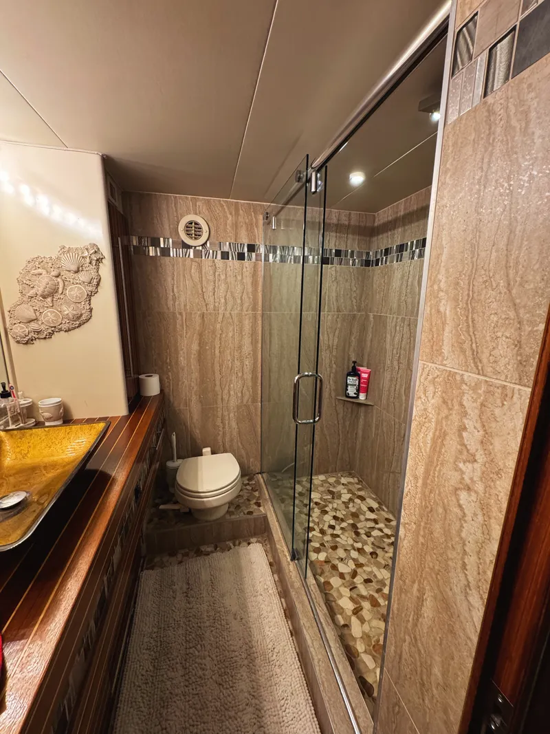 Slide: The Image of The yacht's bathroom features a spacious shower with a glass door, a sink, and a toilet. - 45