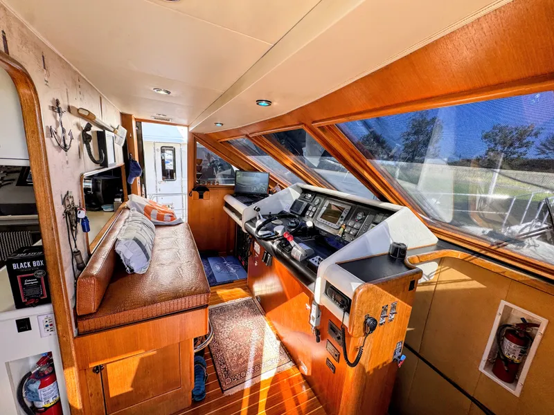 Slide: The Image of Interior of a yacht with wood paneling, helm console, and seating area. Large windows provide ample light. - 25