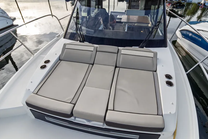 Slide: The Image of 2025 Jeanneau NC 895 Series 2 boat with cushioned sun deck, docked at marina. - 30