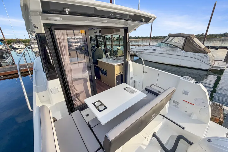 Slide: The Image of 2025 Jeanneau NC 895 Series 2 boat interior with seating and table at marina. - 2