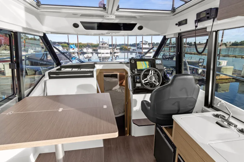 Slide: The Image of Interior of 2025 Jeanneau NC 895 Series 2 boat, featuring helm, seating, and marina view. - 6