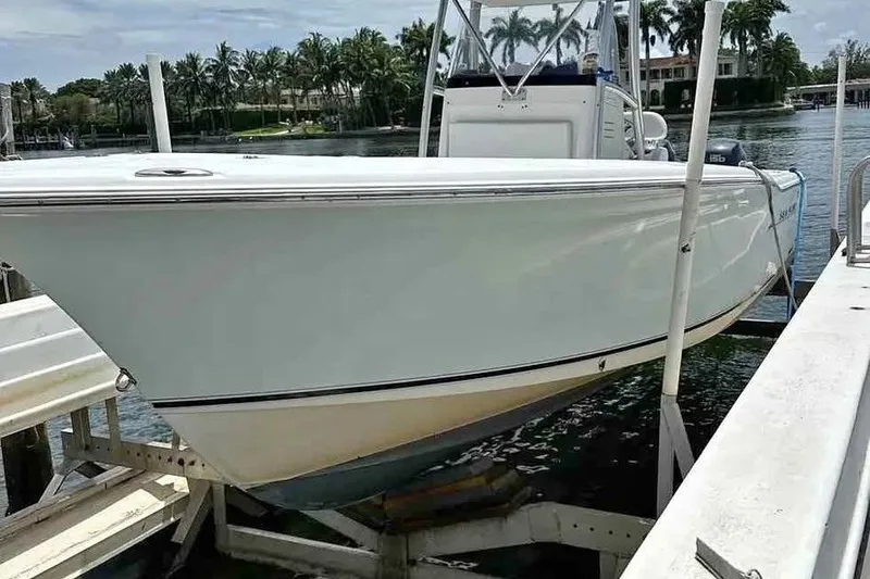 The Image of 2006 Sea Hunt Triton 260 boat docked by palm trees and waterfront homes. - 0