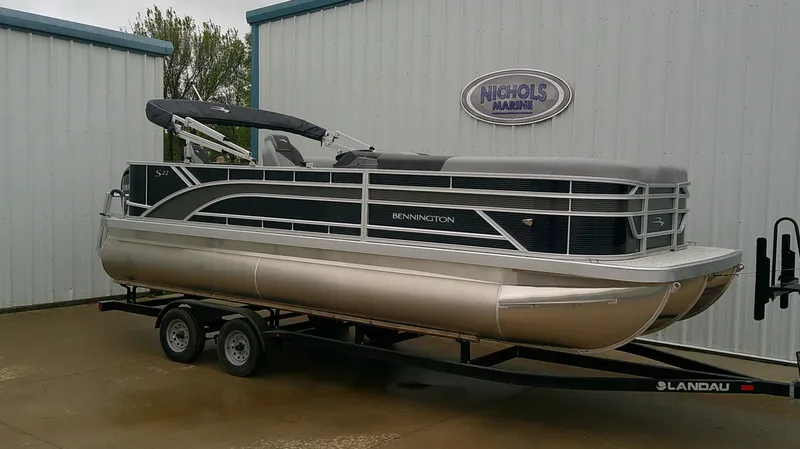 The Image of A Bennington 22 SFC pontoon boat on a trailer in front of a building. - 0
