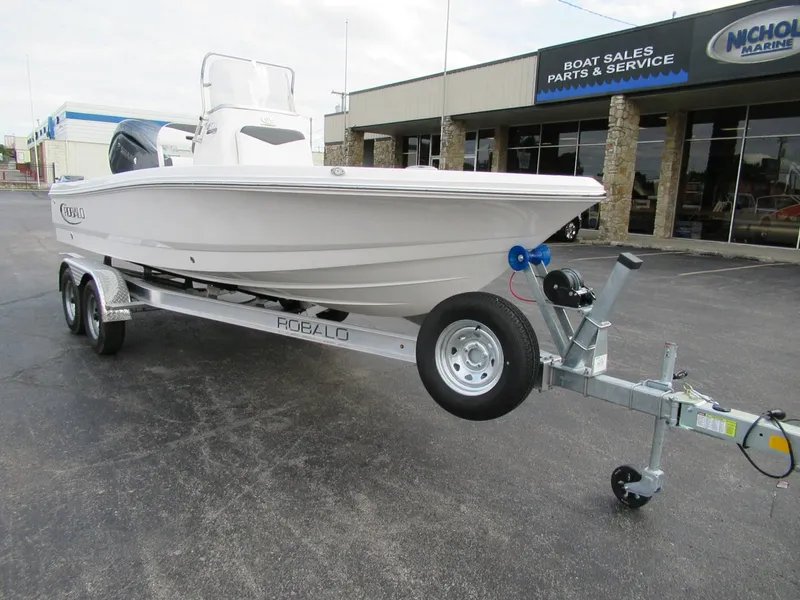 The Image of A white 2027 Robalo 206 Pro boat on a trailer in front of a boat sales shop. - 0