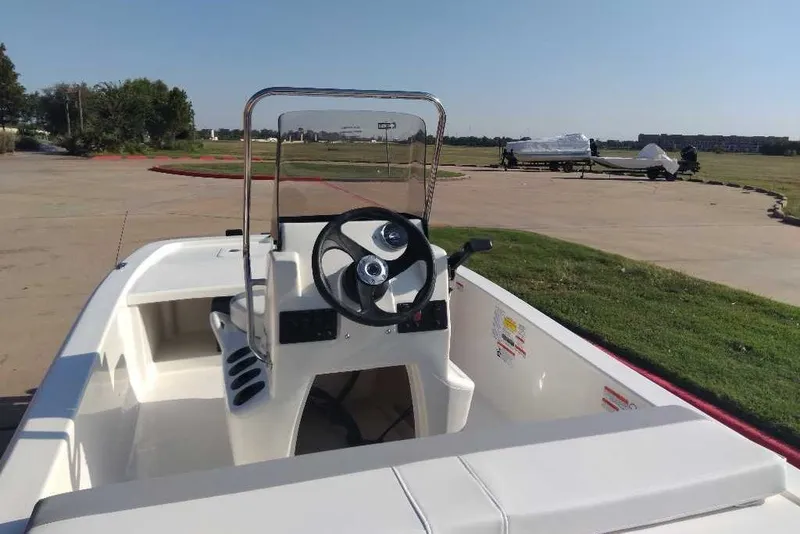 Slide: The Image of 2026 Mako Pro Skiff 13 CC boat with steering console, parked outdoors on a sunny day. - 4