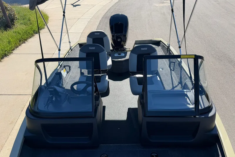 Slide: The Image of 2027 Tracker Pro Guide V-16 WT boat with dual consoles and seating, parked on a sunny street. - 21