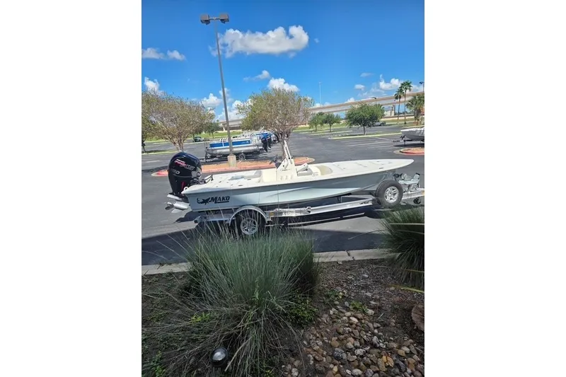 Slide: The Image of 2026 Mako 18 Pro Skiff boat on trailer in parking lot under blue sky. - 13