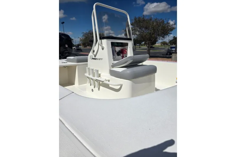 Slide: The Image of 2026 Mako 18 Pro Skiff boat interior with seating and rod holders under a clear blue sky. - 8